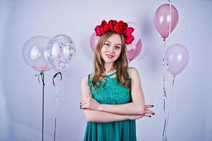 Happy girl in green turqoise dress and wreath with colored balloons isolated on white. Celebrating birthday theme. photo