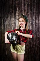 Young funny housewife in checkered shirt and yellow shorts pin up style with kitchen sieve on wooden background. photo