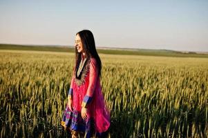 Tender indian girl in saree, with violet lips make up posed at field in sunset. Fashionable india model. photo