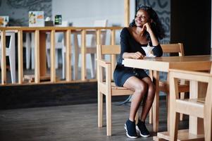 African american girl sitting at cafe and eating ice cream. photo