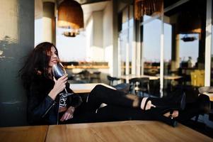 Young curly woman enjoying  her wine in a bar. photo