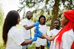 un grupo de felices voluntarios africanos puso las manos en las manos en el parque. Concepto de voluntariado, caridad, personas y ecología de África. foto