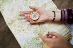 Close-up photo of female hands with compass on a map.