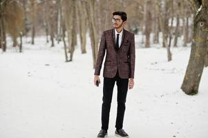 Stylish indian student man in brown suit and glasses posed at winter day outdoor. photo