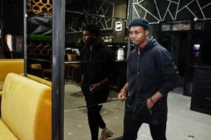 Handsome african american man posing  inside night club in black hat. photo