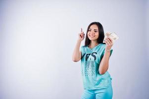 Portrait of an attractive girl in blue or turquoise t-shirt and trousers posing with a lot of money in her hand. photo