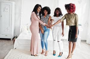 Four best friends. Young adrican women having fun and spend time together, stacking hands and then up. photo