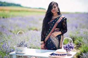 hermosa niña india usa vestido tradicional saree india en campo de lavanda púrpura. foto