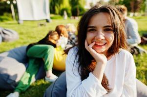 joven grupo multiétnico de personas viendo películas en poof en cine al aire libre. Cierra el retrato de una chica divertida. foto