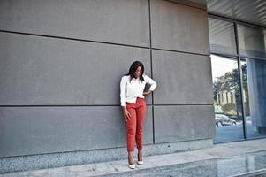 Formally dressed african american business woman in white blouse and red trousers. Successful dark skinned businesswoman. photo