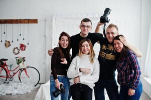 Group of five peoples, friends photographers and designers on studio shooting after hard work day. They happy and laughing. photo