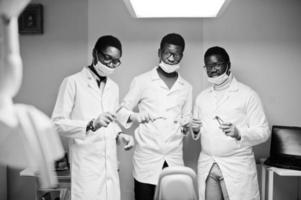 Three african american male doctors colleagues with tools at hands in clinic. photo