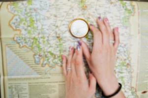 Close-up photo of female hands with compass on a map.