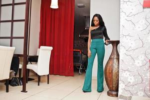 Beauty slim african american model wear on black blouse and green long legs pants posed at chinese cafe. photo