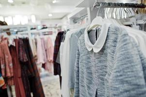 conjunto de ropa colorida femenina en los estantes de la tienda de ropa nueva boutique moderna. foto