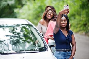 Group of five happy african american traveler girls making selfie against car. photo