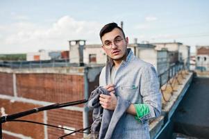 hombre macho con estilo soñador en traje gris y gafas posadas en el techo. foto