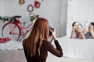 Close up back of young girl photographer shooting on studio two girls while they make their own masks cream . Professional photographer on work. photo