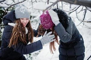 dos amigas divertidas divirtiéndose en el día de invierno cubierto de nieve cerca de árboles cubiertos de nieve. foto