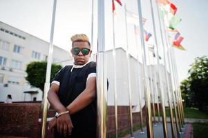 Stylish arabian muslim boy with originally hair posed on streets, against flags of different countries. photo