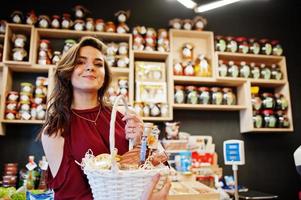 chica de rojo con diferentes productos en la cesta en la tienda de delicatessen. foto