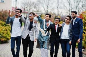 Group of six south asian indian mans in traditional, casual and business wear walking and shows fingers to something. photo