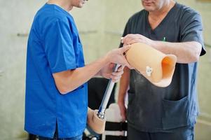 Two prosthetist man workers with prosthetic leg working in laboratory. photo