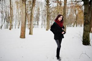 Brunette girl in green sweater, coat and red scarf outdoor on evening winter day. photo