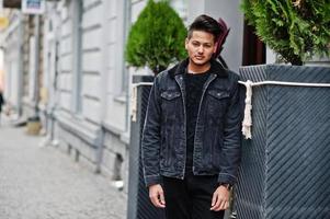 Handsome and fashionable indian man in black jeans jacket posed outdoor. photo