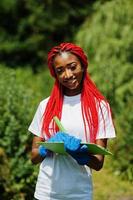 African red haired volunteer woman with clipboard in park. Africa volunteering, charity, people and ecology concept. photo