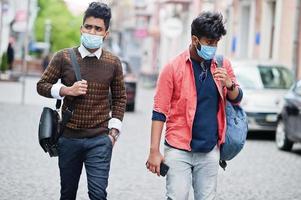 Coronavirus covid-19 concept. Two south asian indian man wearing mask for protect from corona virus walking at city. New normal lifestyle post pandemic in India. photo