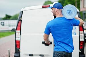 Delivery man in front cargo van delivering bottles of water. photo