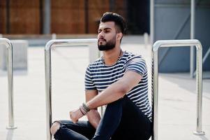 Handsome tall arabian beard man model at stripped shirt posed outdoor. Fashionable arab guy. photo