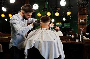 Handsome bearded man at the barbershop, barber at work. photo