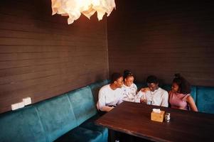 felices amigos africanos sentados y charlando en el café. grupo de personas negras reunidas en un restaurante. foto