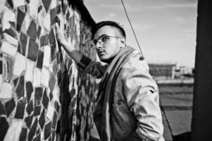 Dreamer stylish macho man in gray suit, scarf and glasses posed on the roof. photo