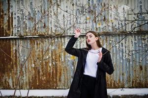 Fashionable long legs brunette model in long black cloak posed outdoor at winter day. photo