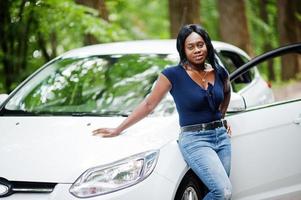 African american woman posed against white car in forest road. photo