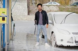 hombre del sur de asia o hombre indio lavando su transporte blanco en el lavado de autos. foto