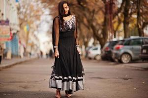 linda chica india con vestido de sari negro posó al aire libre en la calle de otoño. foto