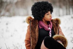 Curly hair african american woman wear on sheepskin coat and gloves posed at winter day. photo