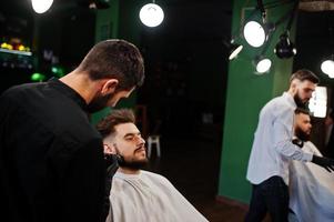 apuesto hombre barbudo en la barbería, peluquero en el trabajo. foto