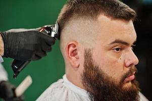 Handsome bearded man at the barbershop, barber at work. photo