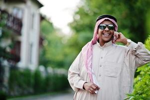hombre de negocios árabe del medio oriente posó en la calle con gafas de sol, hablando por teléfono móvil. foto