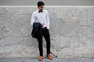 Young indian man on black suit and bow tie posed outdoor. photo