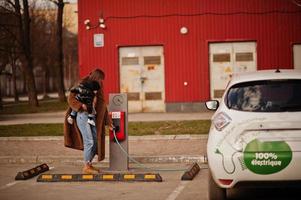 Young mother with child charging electro car at the electric gas station. photo