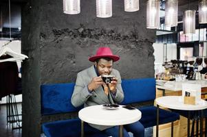 Stylish African American man model in gray jacket tie and red hat drink coffee at cafe. photo