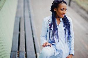 Stylish african american girl with dreads holding mobile phone at hand, outdoor snowy weather. photo