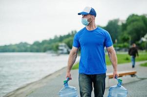 Delivery water man wear protective face medical mask during coronavirus pandemia. photo