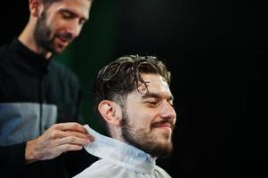 apuesto hombre barbudo en la barbería, peluquero en el trabajo. foto